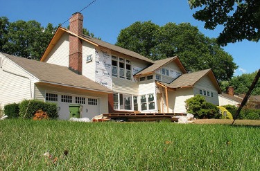 Unpainted fiber cement siding is being added to this home, with house wrap insulation. Photo by Chaim Zvi on Flickr.